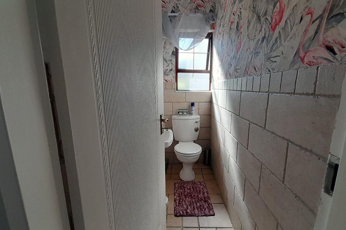 A compact bathroom featuring tiled walls, a standard toilet, and a basin, with a window providing natural light.