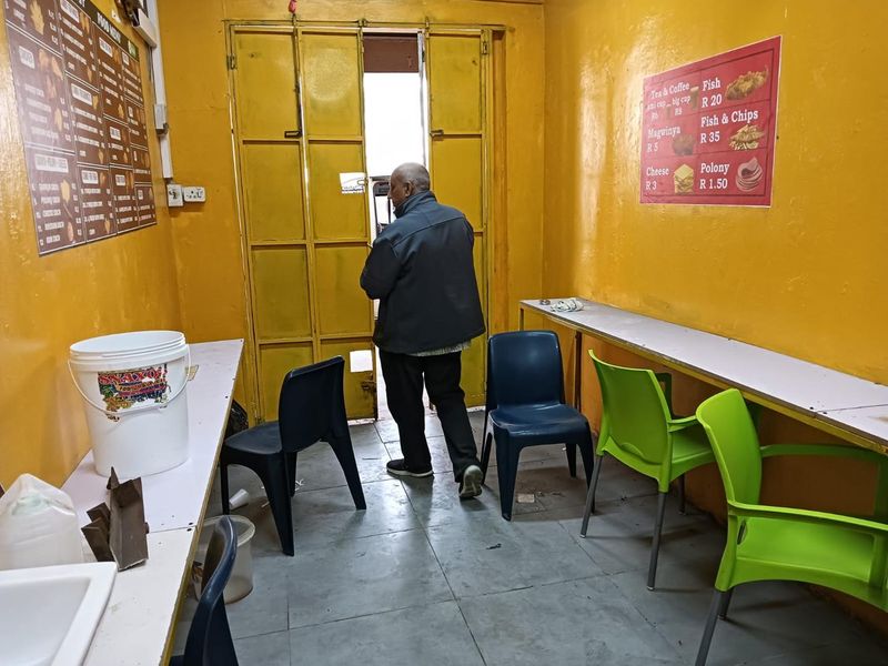 A functional commercial kitchen space featuring built-in counters, tiled flooring, and yellow painted walls, currently set up for food service.