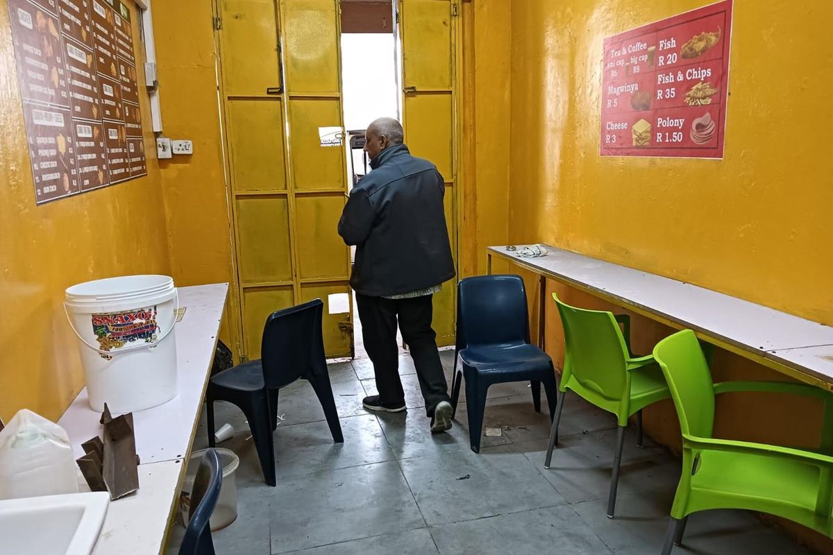 A functional commercial kitchen space featuring built-in counters, tiled flooring, and yellow painted walls, currently set up for food service.