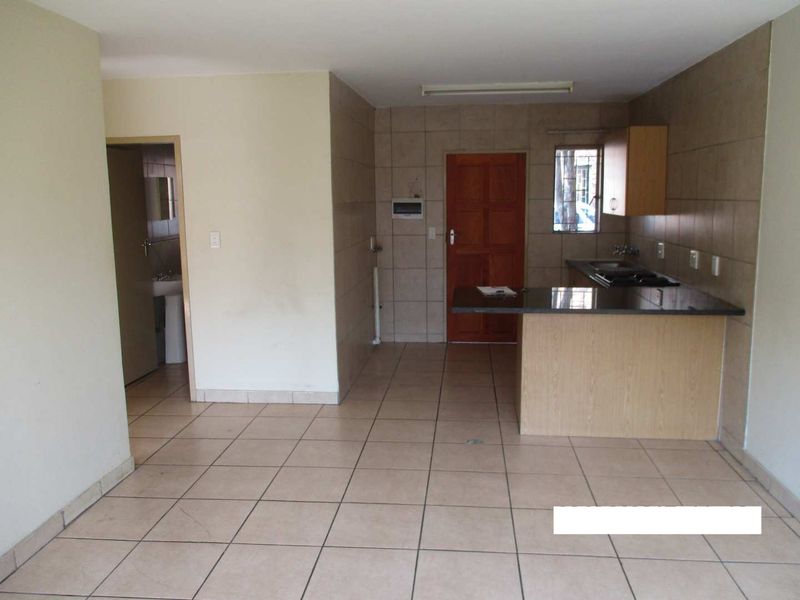Open plan living area featuring tiled flooring and a functional kitchen with granite countertops, built-in cabinetry, and a hob.