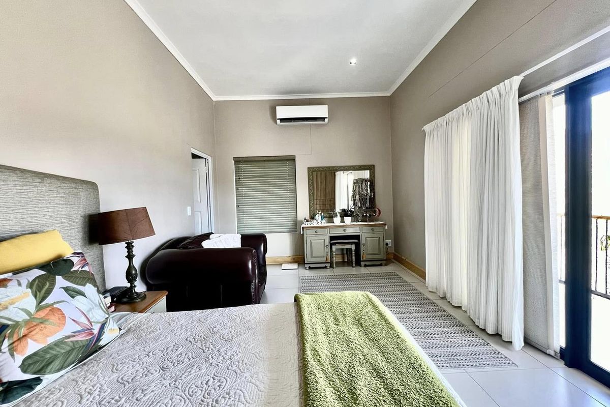 Spacious bedroom featuring tiled flooring, a wall-mounted air conditioning unit, and large sliding glass doors providing access to an outdoor area.