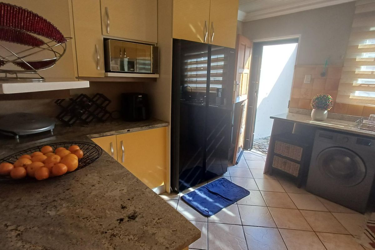 A functional kitchen featuring built-in cabinetry, stone-look countertops, and direct access to an exterior area, providing a practical layout for daily use.