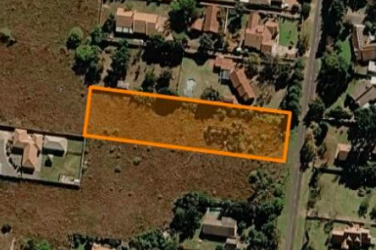 Aerial view of a vacant residential plot highlighted in an orange boundary, situated within an established suburban neighborhood.