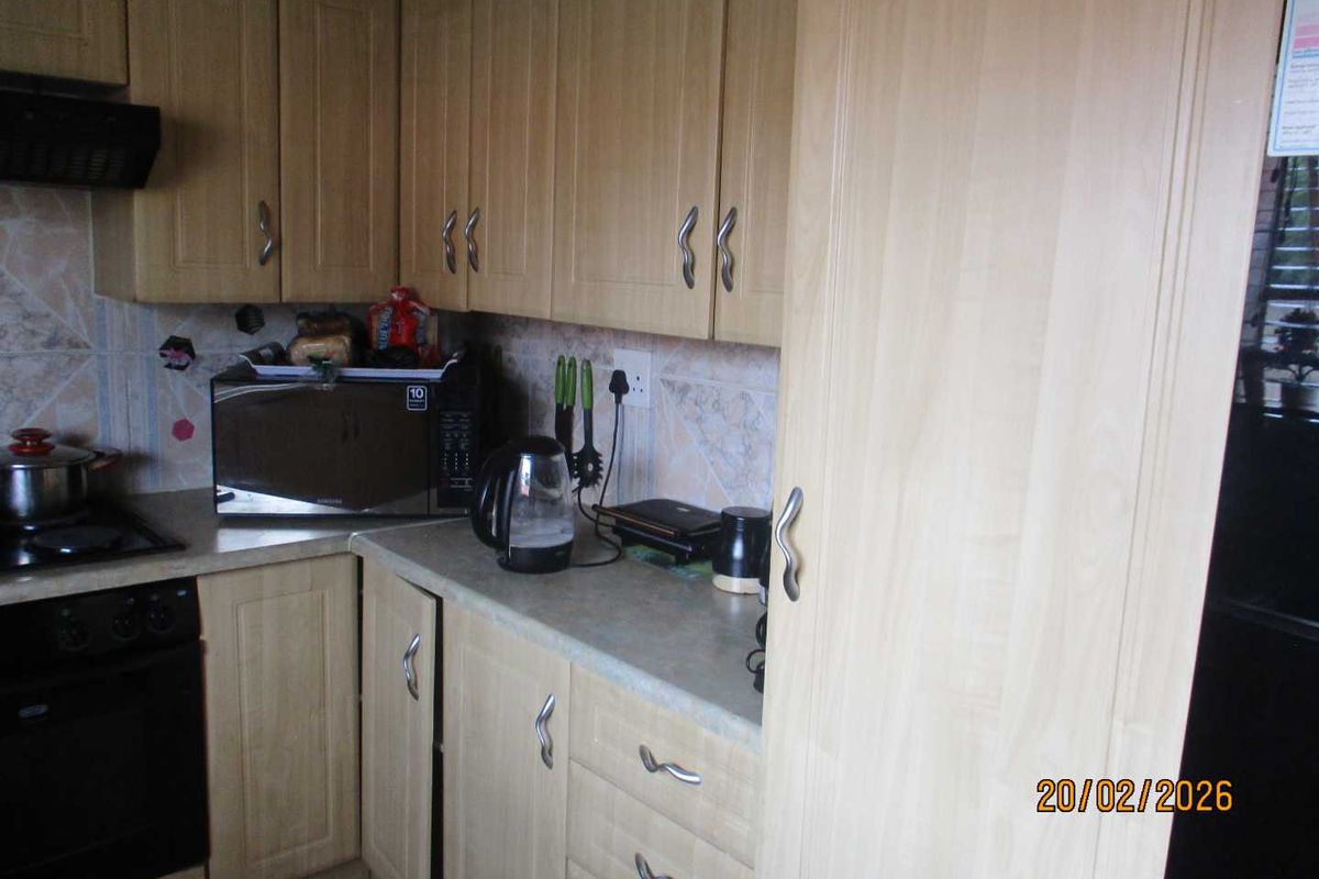 A functional kitchen featuring light wood-finish cabinetry, laminate countertops, a built-in oven, and an extractor fan.