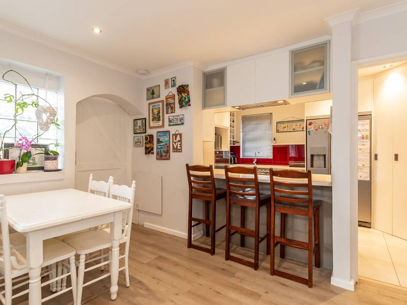 Open plan dining area featuring a breakfast bar, modern cabinetry, and a red glass splashback, seamlessly connecting to the kitchen and utility space.