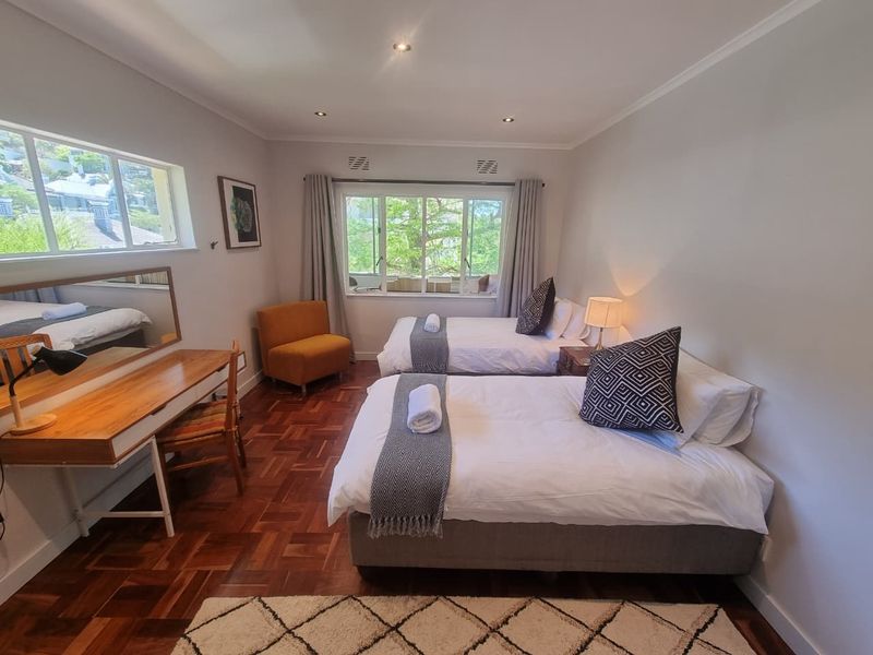A well-lit bedroom featuring classic parquet flooring, recessed ceiling lighting, and large windows providing natural light and garden views.
