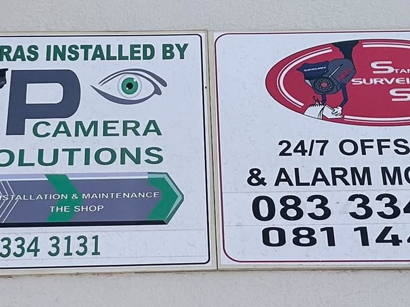 Close-up view of security company signage mounted on the exterior wall of the property.