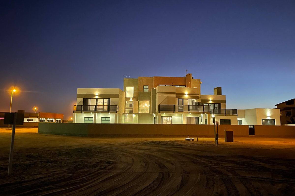 A modern multi-level residence at dusk, featuring expansive balconies with glass balustrades, contemporary architectural design, and integrated exterior lighting.