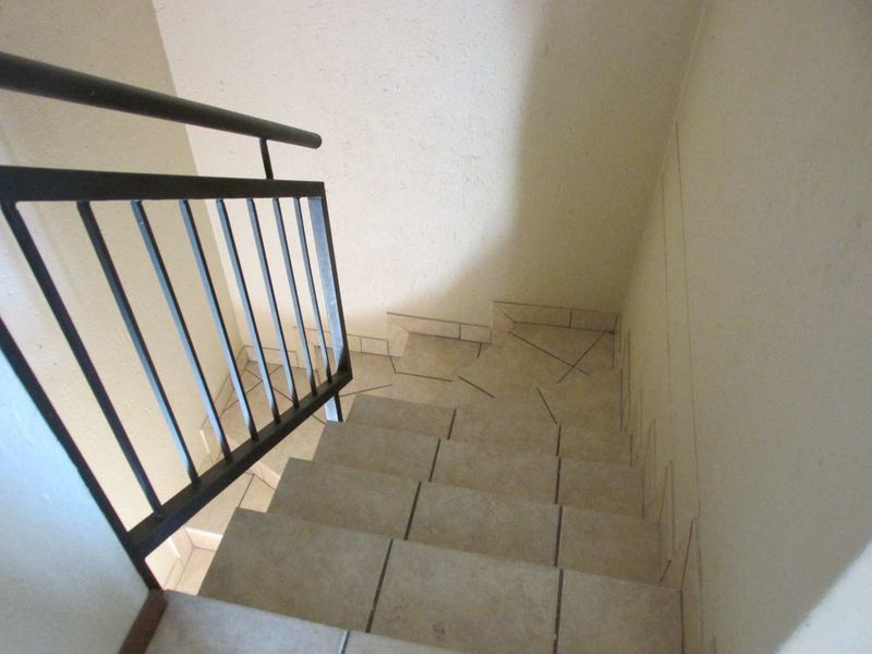 A functional staircase featuring tiled steps and a black metal handrail, providing access between levels within the apartment.