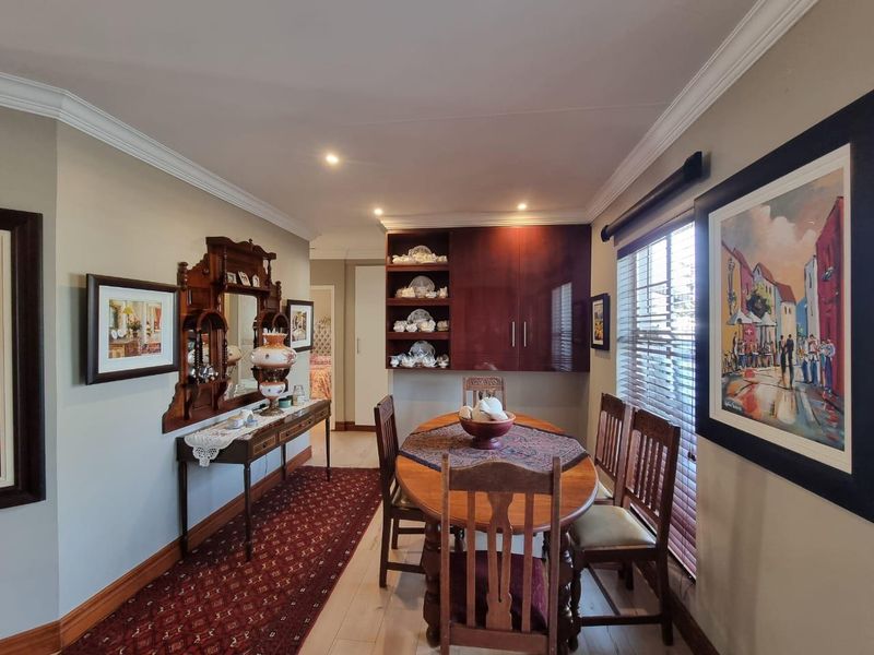A well-maintained dining room featuring built-in cabinetry, recessed lighting, crown molding, and large windows with venetian blinds.