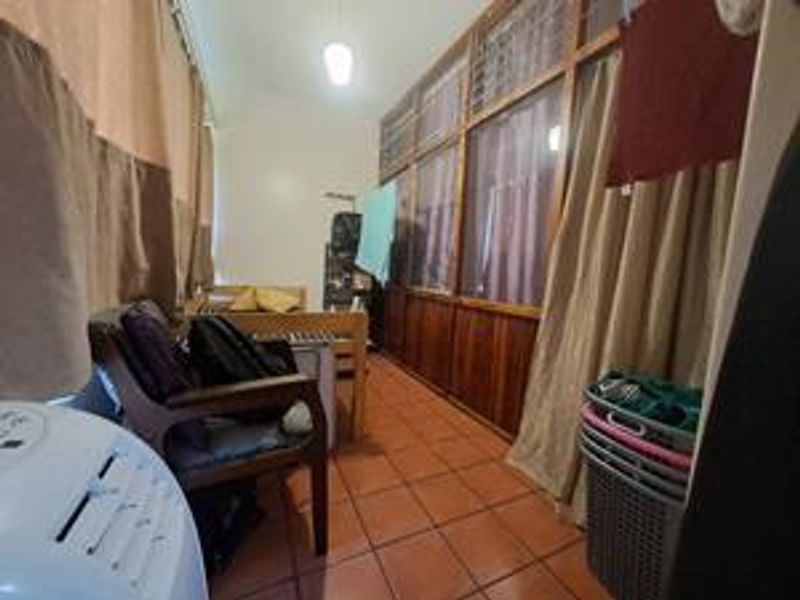 A covered balcony or enclosed patio area featuring tiled flooring and a wooden-framed glass partition wall.