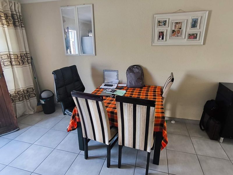 A functional dining area featuring neutral tiled flooring and a solid wooden door, providing a practical space for meals.