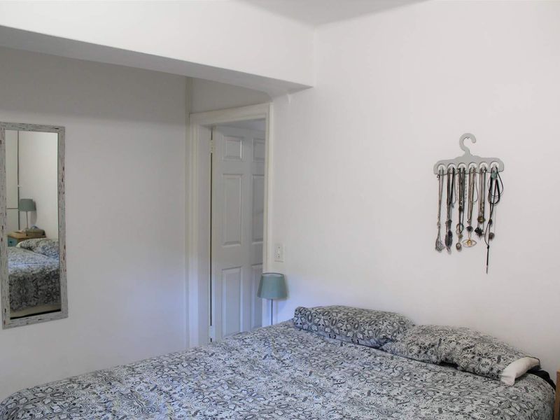 A simple bedroom interior featuring white walls and a standard panel door leading to an adjacent space.