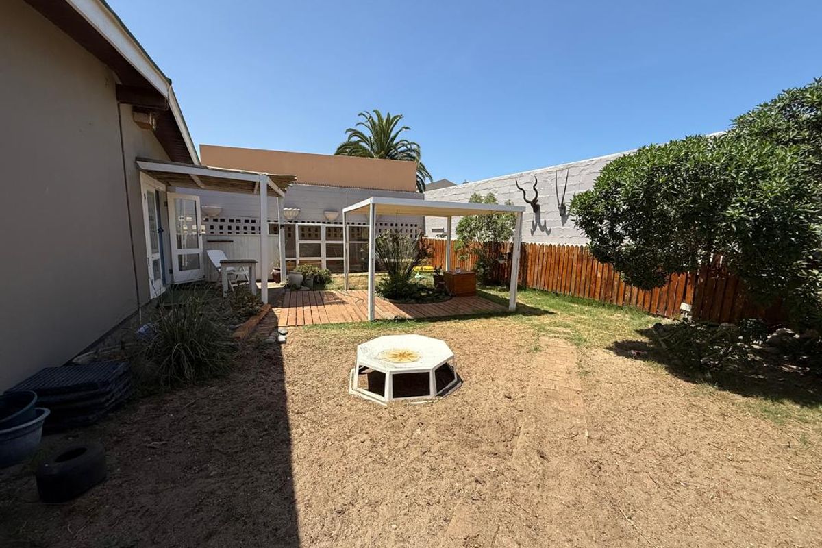 A rear garden area featuring a timber deck, a pergola structure, and perimeter fencing, offering potential for landscaping and outdoor living improvements.