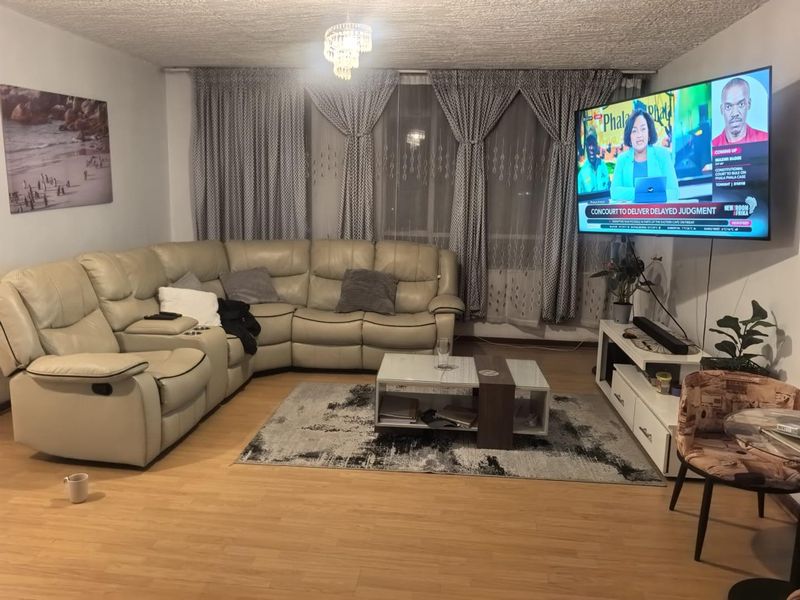 A comfortable living room featuring laminate flooring and large window treatments, providing a functional and inviting space for relaxation.