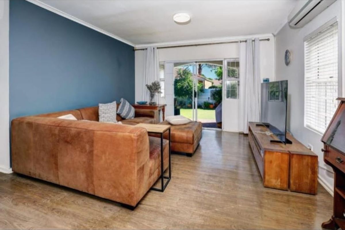 A comfortable living room featuring laminate flooring, a feature wall, and a sliding glass door providing direct access to the rear garden.