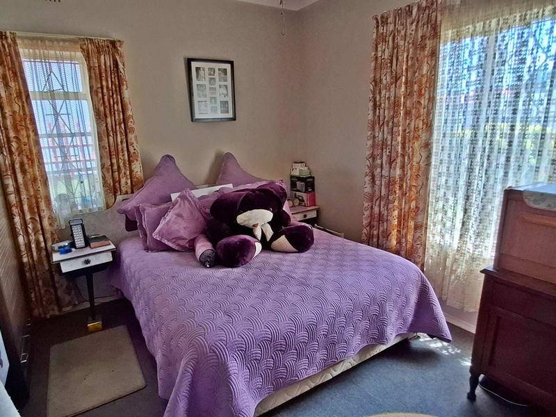 A standard bedroom featuring dual windows with curtains and a built-in wardrobe, offering a functional space with neutral wall finishes.
