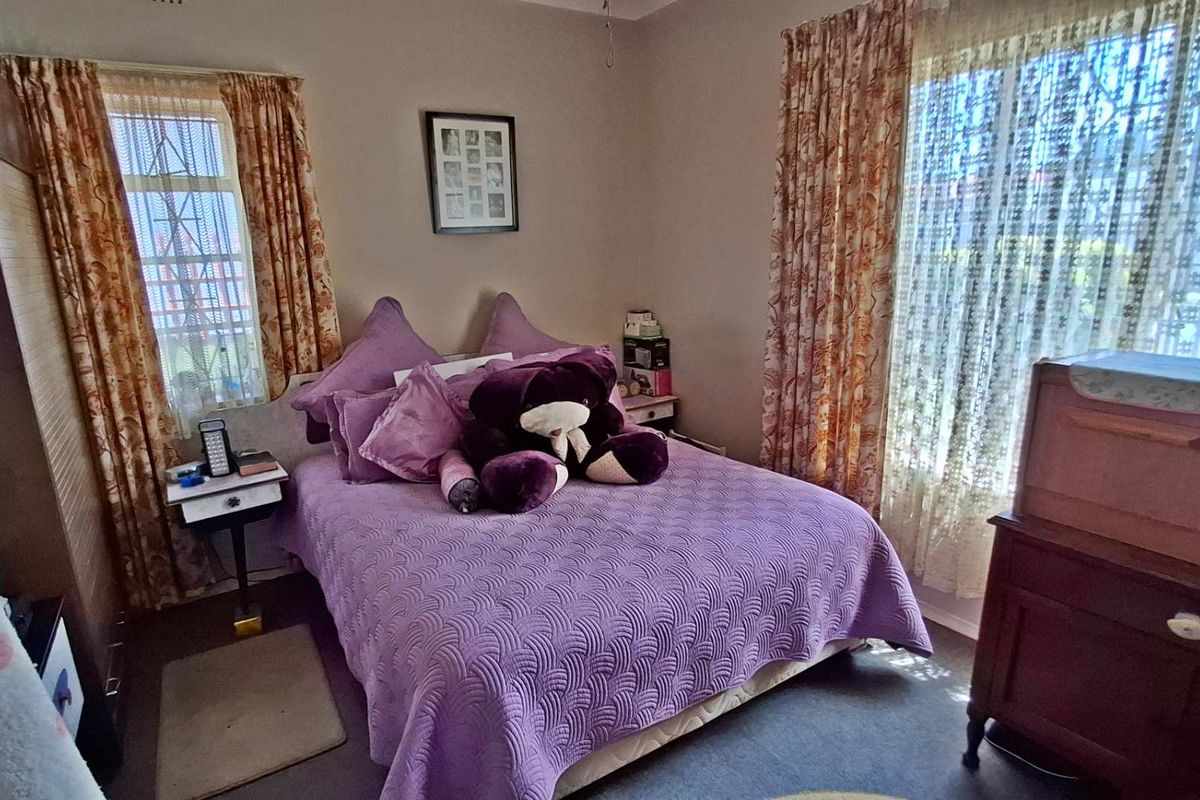 A standard bedroom featuring dual windows with curtains and a built-in wardrobe, offering a functional space with neutral wall finishes.