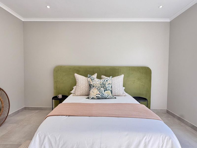 A well-maintained bedroom featuring neutral wall tones, modern tiled flooring, and recessed ceiling lighting, providing a clean and contemporary living space.