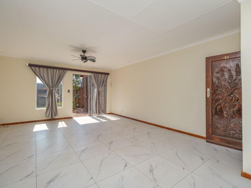 Spacious living area featuring modern marble-look floor tiles, a ceiling fan, and direct access to an outdoor patio through sliding glass doors.