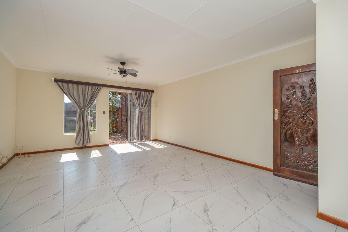 Spacious living area featuring modern marble-look floor tiles, a ceiling fan, and direct access to an outdoor patio through sliding glass doors.