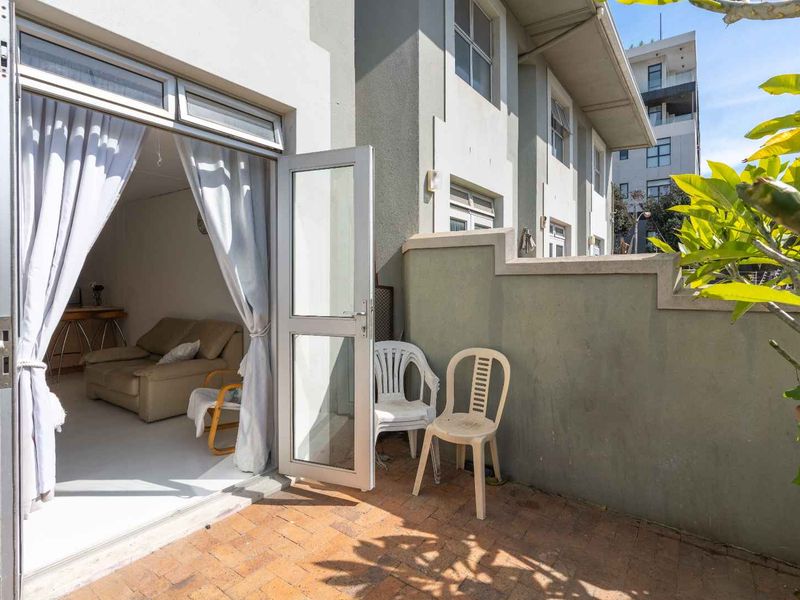 A private outdoor patio area featuring brick paving and a boundary wall, providing direct access to the interior living space through a sliding door.