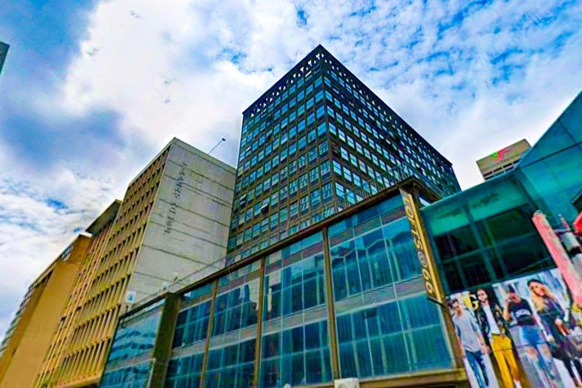 A low-angle exterior view of a modern multi-story apartment building featuring a glass facade and steel structural elements.