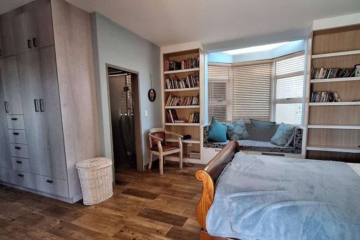 Spacious bedroom featuring built-in cabinetry, integrated shelving units, and a cozy window seat with natural light.