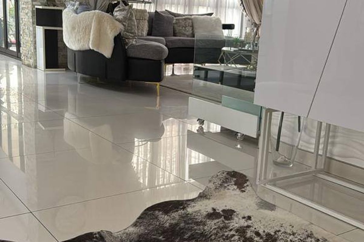 Modern living room featuring polished porcelain floor tiles, a textured feature wall, and a recessed ceiling design with integrated lighting.
