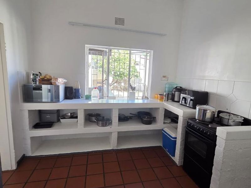 A functional kitchen featuring masonry cabinetry, tiled flooring, and a freestanding stove, offering a basic layout with potential for modern updates.