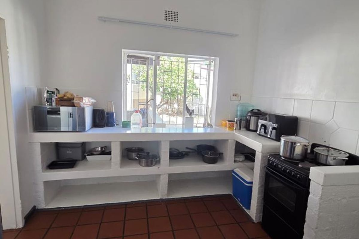 A functional kitchen featuring masonry cabinetry, tiled flooring, and a freestanding stove, offering a basic layout with potential for modern updates.