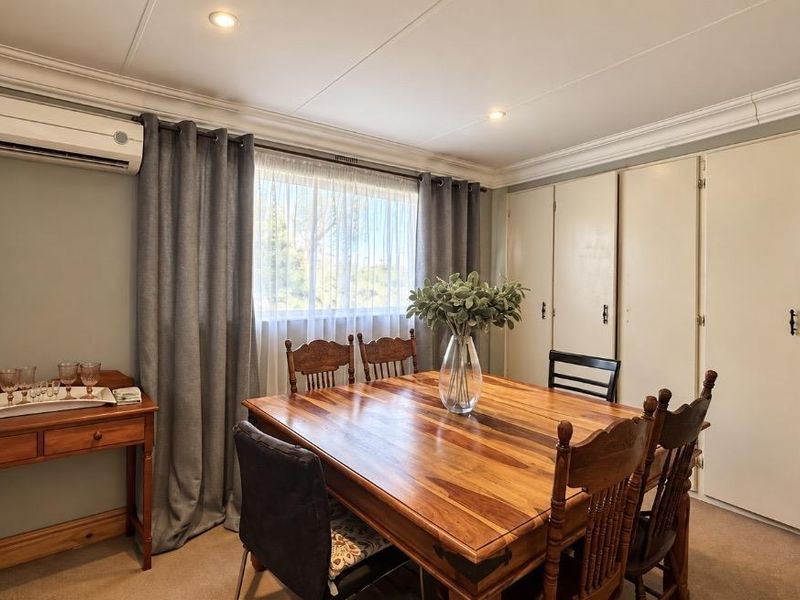 A well-maintained dining room featuring built-in storage cupboards, a split-system air conditioner, and recessed downlighting, offering a functional and comfortable space for meals.