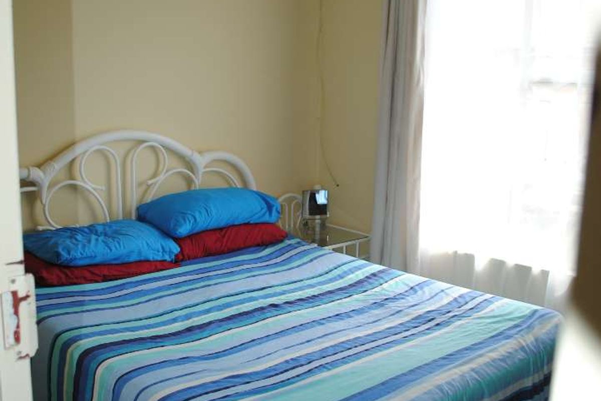 A compact bedroom featuring tiled flooring and a window with natural light, providing a functional space for rest.