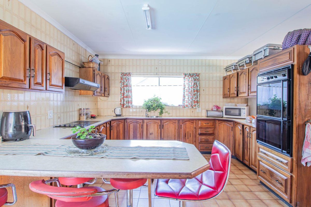 A functional kitchen featuring traditional wooden cabinetry, a built-in oven, a breakfast nook, and tiled finishes throughout.