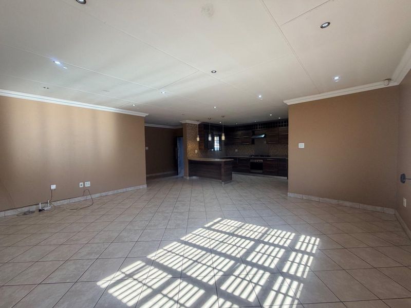 Spacious open-plan living area featuring tiled floors, recessed lighting, and a functional kitchen with built-in cabinetry and appliances.