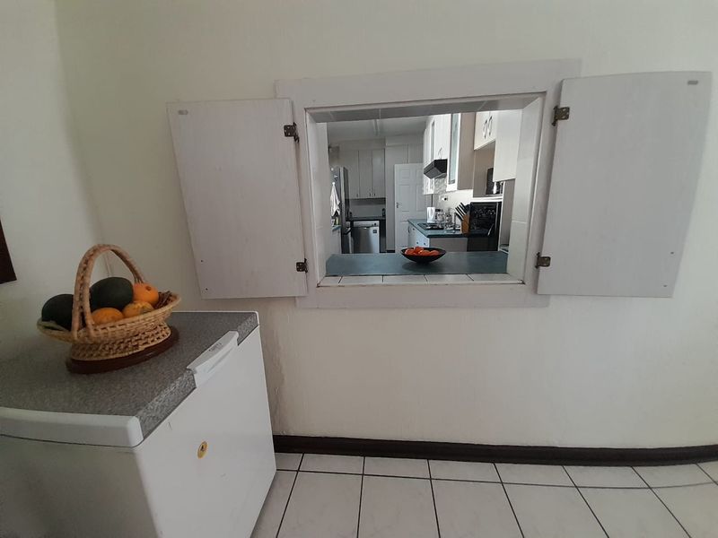 A kitchen view through a serving hatch, featuring tiled flooring and built-in cabinetry with a functional layout.