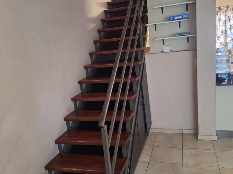 A functional hallway featuring a modern metal and wood staircase with integrated under-stair storage and tiled flooring.