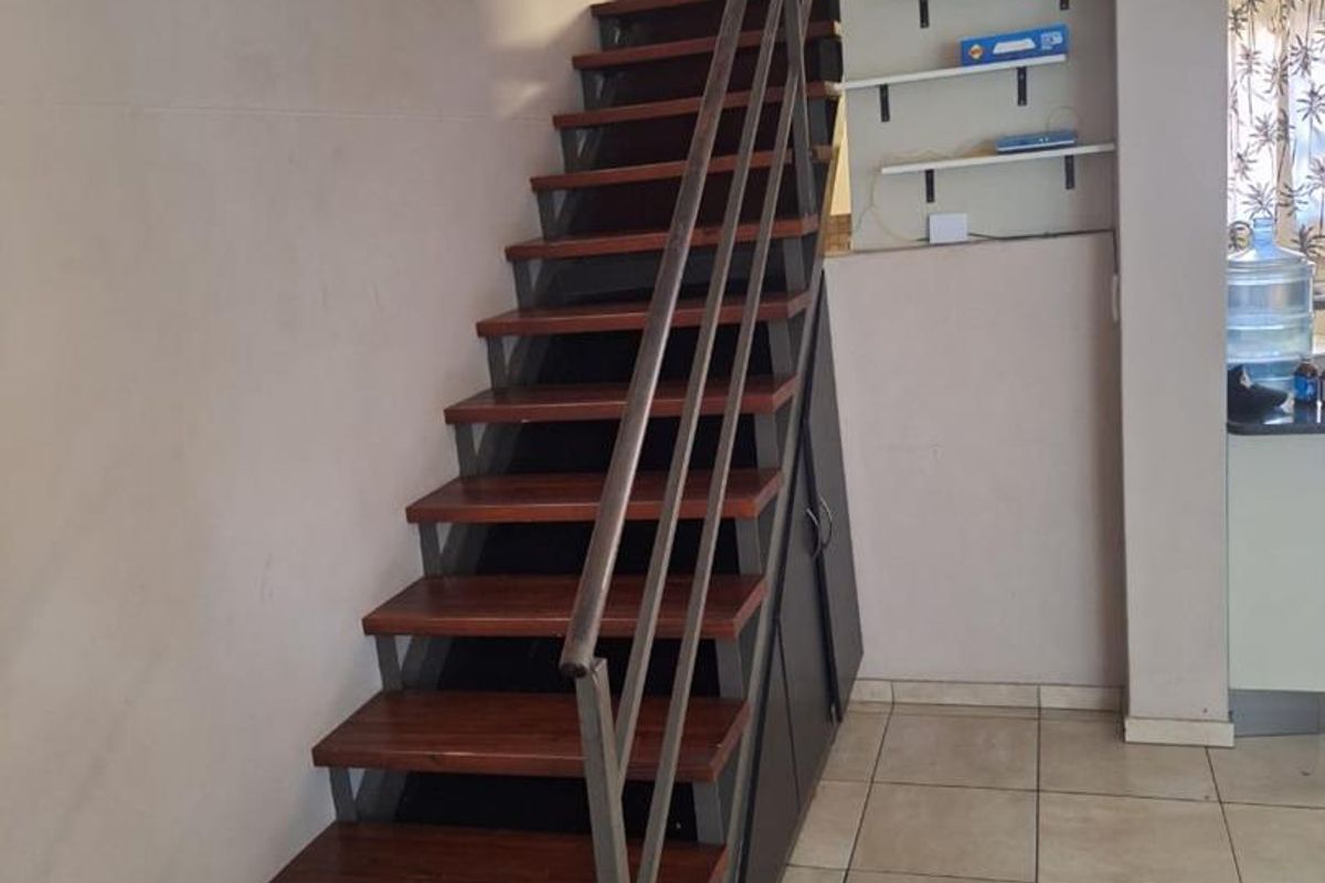 A functional hallway featuring a modern metal and wood staircase with integrated under-stair storage and tiled flooring.