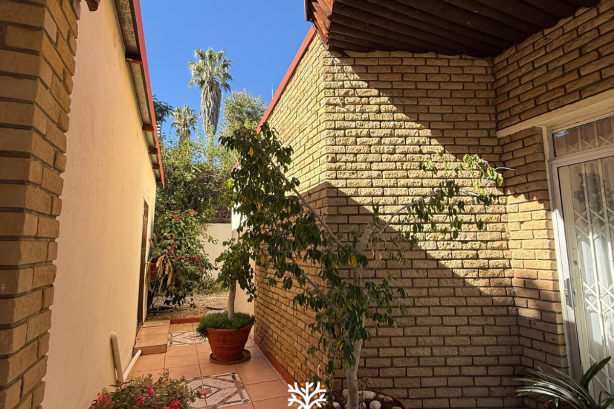 A side courtyard area featuring tiled flooring and exposed brick walls, providing a private outdoor transition space between building sections.