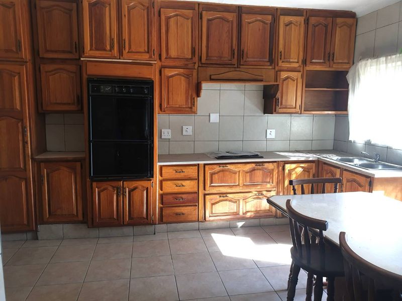A functional kitchen featuring extensive built-in wooden cabinetry, a built-in oven, cooktop, and tiled finishes throughout.