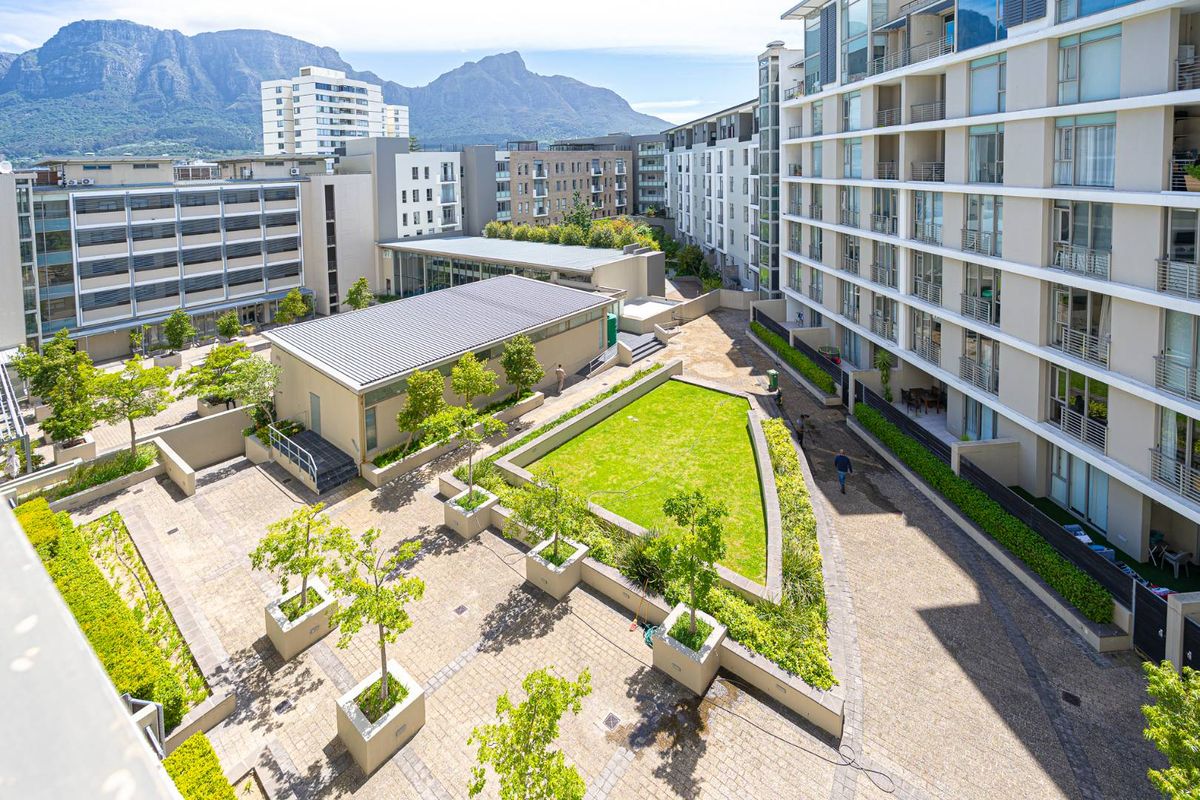 An elevated aerial view of a modern apartment complex courtyard featuring landscaped gardens, paved walkways, and well-maintained communal outdoor spaces.