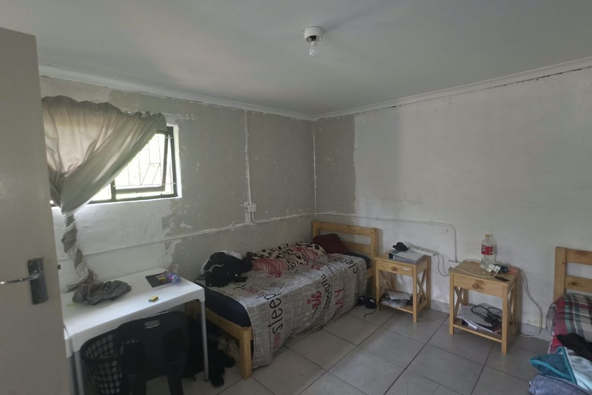A bedroom featuring tiled flooring and exposed electrical conduit, currently requiring wall finishing and painting to improve the overall aesthetic and condition.