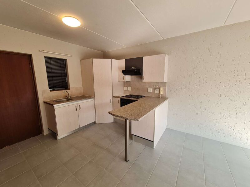 A functional kitchen featuring light-toned built-in cabinetry, a breakfast bar, tiled flooring, and integrated cooking appliances.