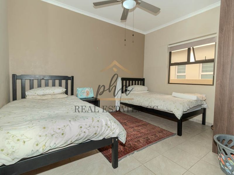 A functional bedroom featuring tiled flooring, a ceiling fan, and a built-in wardrobe, providing practical storage and comfortable living space.