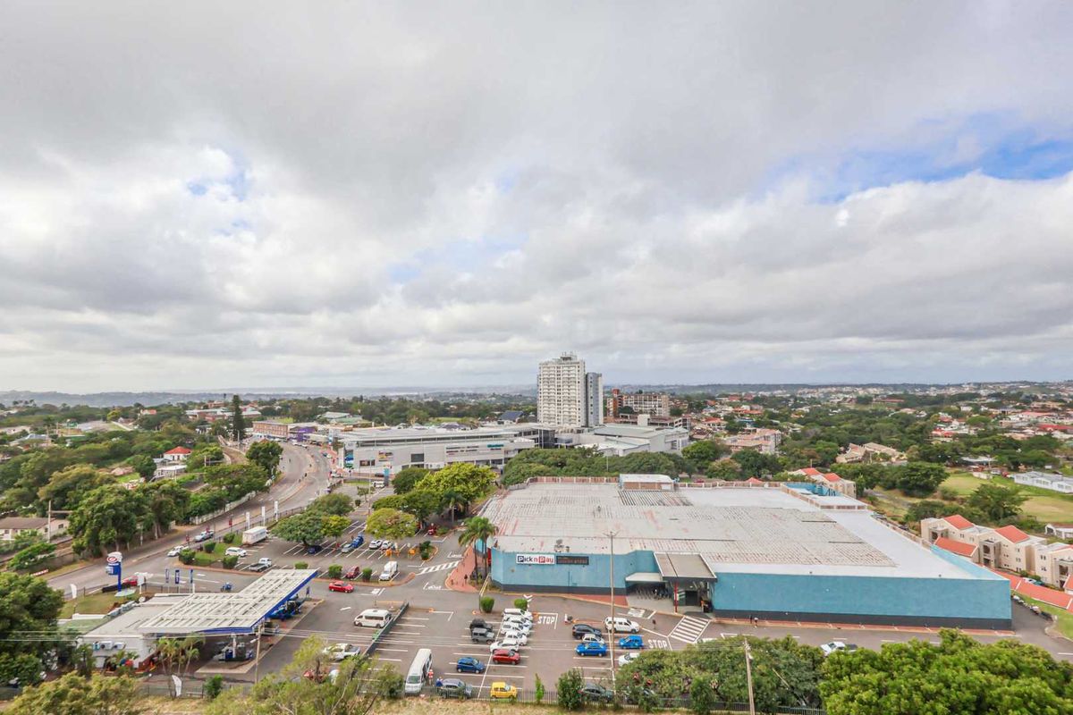 An elevated aerial view overlooking the surrounding urban landscape, including nearby commercial centers, parking facilities, and residential areas.