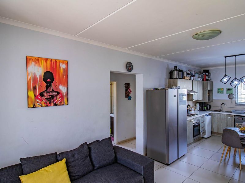 Open-plan living and kitchen area featuring tiled floors, built-in cabinetry, and integrated kitchen appliances, providing a functional and connected living space.