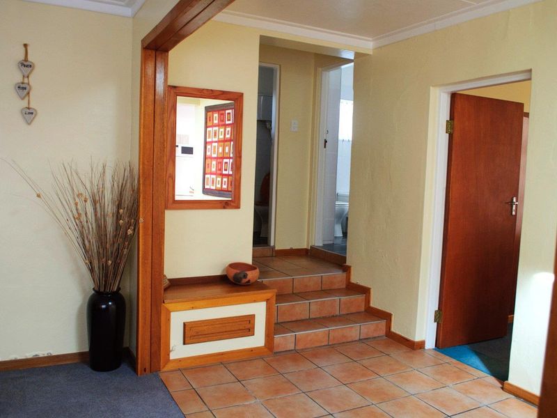 A functional hallway featuring tiled flooring, timber door frames, and built-in cabinetry, providing access to adjacent rooms via a small set of tiled steps.