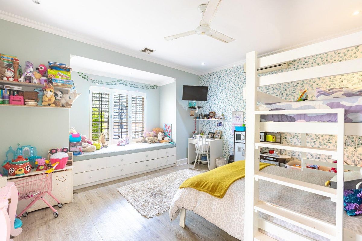 Spacious bedroom featuring a built-in window seat with storage drawers, ceiling fan, and split-system air conditioning unit.