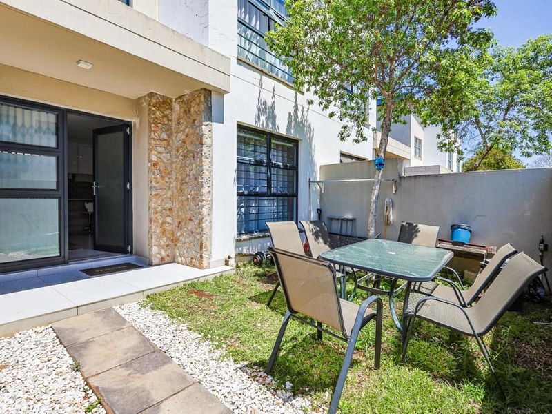 A private rear courtyard featuring a tiled patio area, stone-clad accents, and a small garden space with a paved walkway.