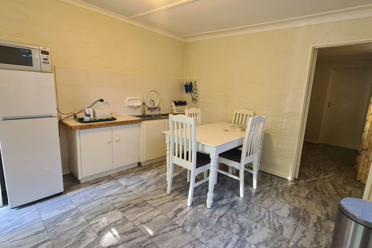 A functional kitchen area featuring built-in cabinetry, a sink, and tiled flooring, providing a practical space for meal preparation and dining.